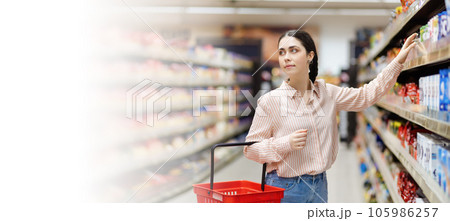 Web banner of shopping in supermarket. Portrait of young attractive caucasian woman takes food from shelve. Copy space. Concept of consumerism 105986257