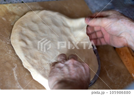 men's hands prepare dough for dumplings on special mold. Close-up 105986880