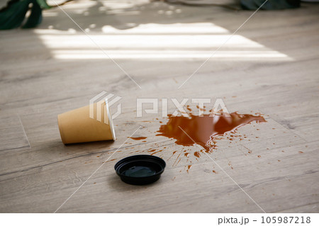 Paper cup of coffee fell on laminate, coffee spilled on floor. 105987218