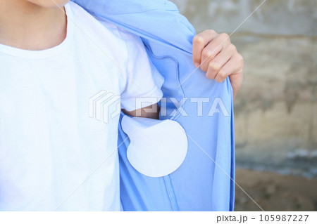 The teenager shows a strip of sweat attached to the armpits of shirt. The teenager shows a strip of sweat attached to the armpits of shirt. 105987227