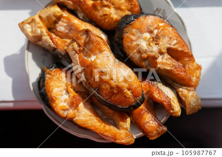 Grilled salmon steaks lie on a plate, beautiful sunlight on the table. Delicious and healthy meal. Grilled salmon steaks lie on a plate, beautiful sunlight on the table. Delicious and healthy meal. 105987767