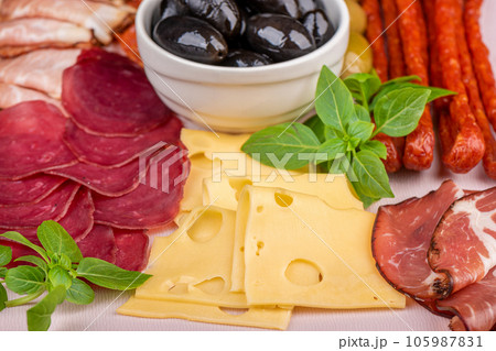 Close-up of slicing cheese, sausages, prosciutto with olives. 105987831