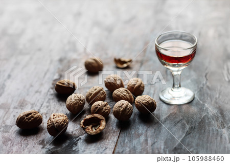 A glass of walnut liquor and walnuts on the old wooden table in backlight 105988460