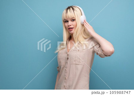 adorable blonde young girl uses headphones to listen to the radio 105988747
