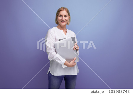 middle-aged woman with blond hair solves work tasks using a laptop 105988748