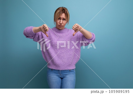 portrait of sad charming pleasant blond young woman in purple sweater with dislike on blue 105989195