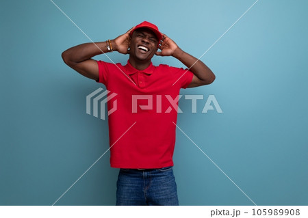 corporate color. handsome african man wearing red t-shirt and cap on background with copy space corporate color. handsome african man wearing red t-shirt and cap on background with copy space 105989908