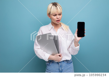 young blond caucasian woman with a short haircut dressed in a white shirt and jeans holds working young blond caucasian woman with a short haircut dressed in a white shirt and jeans holds working 105990234