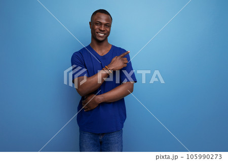 attractive 25s african guy in casual blue t-shirt pointing his finger to the side 105990273
