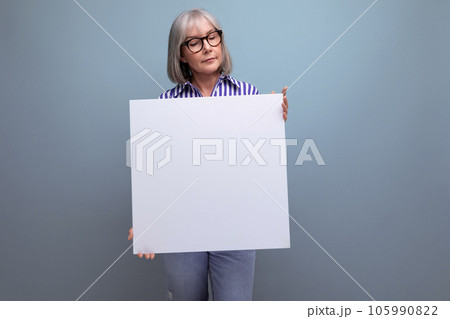 gray-haired mature woman showing blank sheet with mockup on bright studio background gray-haired mature woman showing blank sheet with mockup on bright studio background 105990822