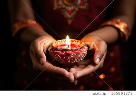 Woman hands with henna holding colorful clay diya lamps lit during diwali celebration 105991875
