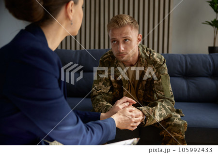 Psychologist holding hand of war veteran or soldier talking about his trauma 105992433