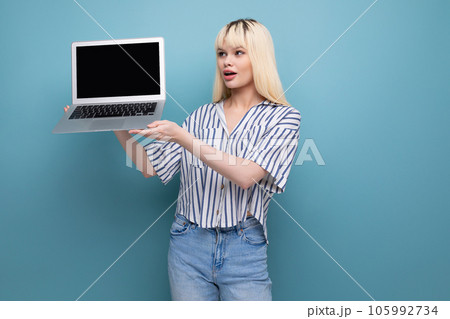 pretty blonde young lady in casual outfit demonstrates laptop screen with mockup 105992734