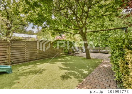 a backyard with a green lawn and wooden fenced in to the back yard there is a blue toy car parked on the grass a backyard with a green lawn and wooden fenced in to the back yard there is a blue toy car parked on the grass 105992778