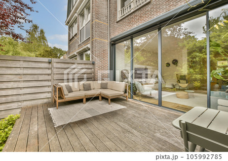 an outside living area with wood flooring and sliding glass doors leading to the decked back yard on a sunny day 105992785