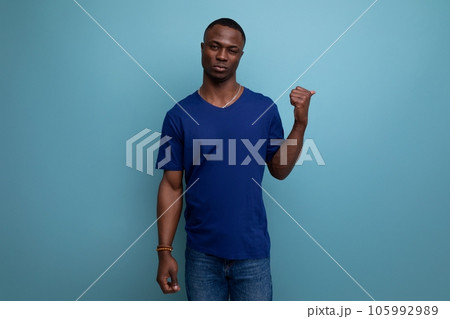 handsome young american man in blue t-shirt shows his hand towards space 105992989