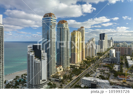 View from above of luxurious highrise hotels and condos on Atlantic ocean shore in Sunny Isles Beach city. Urban street with busy traffic. American tourism infrastructure in southern Florida 105993726