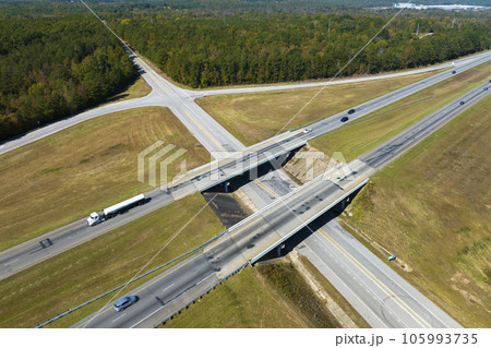 View from above of busy american highway with fast moving traffic between woods. Interstate transportation concept View from above of busy american highway with fast moving traffic between woods. Interstate transportation concept 105993735