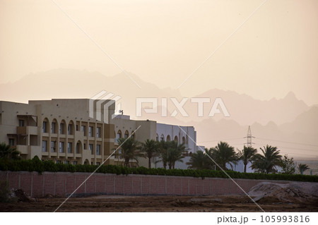 Sunset landscape with remote hotel complex against dark mountain peaks in egyptian desert 105993816