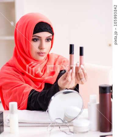 Beautiful woman in hijab applying make-up Beautiful woman in hijab applying make-up 105993842