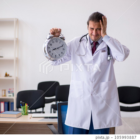 Young male doctor teacher in time management concept 105993887