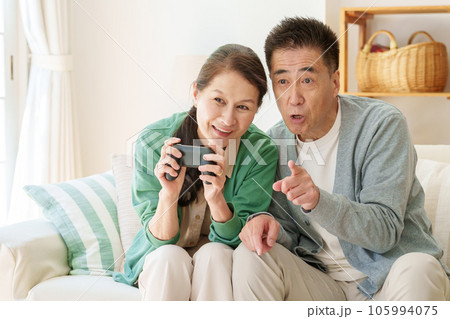 リビングでテレビゲームを楽しむシニア夫婦 リビングでテレビゲームを楽しむシニア夫婦 105994075
