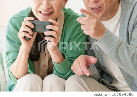 リビングでテレビゲームを楽しむシニア夫婦 105994080