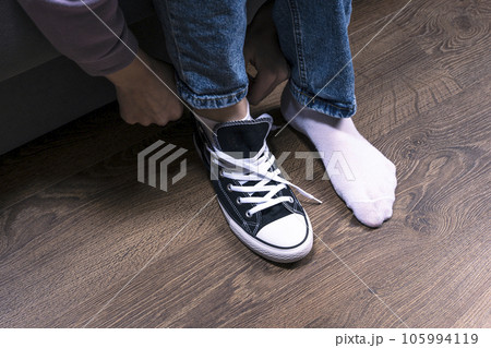 a teenage girl, sitting on the couch in one sneaker. a teenage girl, sitting on the couch in one sneaker. 105994119