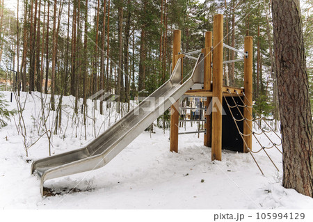 An empty children's slide in a winter amusement park among the pines An empty children's slide in a winter amusement park among the pines 105994129