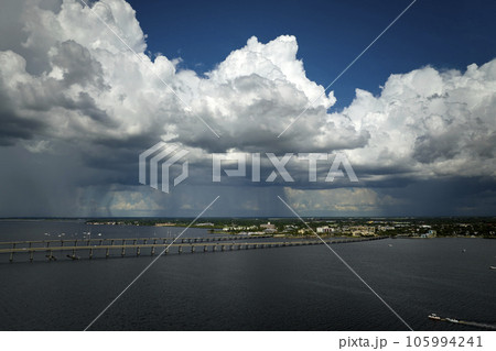 Stormy clouds forming from evaporating humidity of ocean water before thunderstorm over traffic bridge connecting Punta Gorda and Port Charlotte over Peace River. Bad weather conditions for driving 105994241