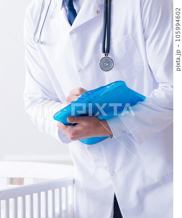 Man male pediatrician near baby bed preparing to examine 105994602
