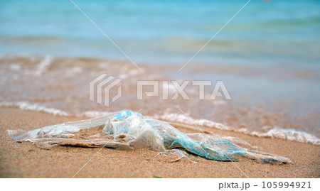 Left behind plastic bag garbage on sandy beach. Empty used dirty litter on sea shore. Environmental pollution. Ecological problem 105994921
