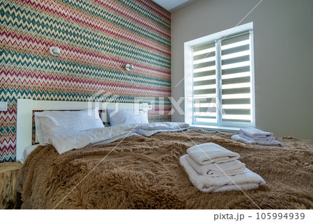 Interior of a spacious hotel bedroom with fresh linen on a big double bed. Cozy contemporary room in a modern house. 105994939