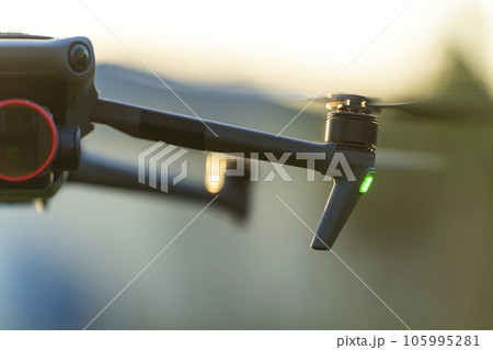 Drone quadcopter with digital camera and fast rotating propellers flying taking video and pictures 105995281