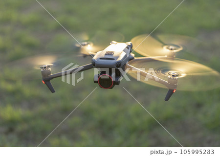 Drone aircraft with blurred fast rotating propellers and video camera flying in air Drone aircraft with blurred fast rotating propellers and video camera flying in air 105995283