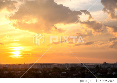 Dramatic sunset rural landscape with puffy clouds lit by orange setting sun and blue sky. Dramatic sunset rural landscape with puffy clouds lit by orange setting sun and blue sky. 105995287