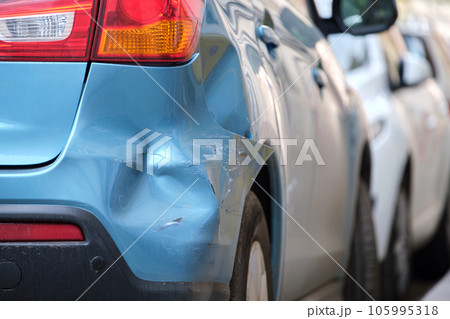 Dented car with damaged fender parked on city street side. Road safety and vehicle insurance concept 105995318