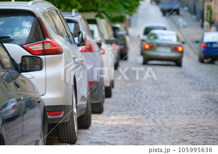 City traffic with cars parked in line on street side. 105995636