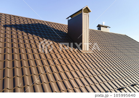 Chimney on house roof top covered with metallic shingles under construction. Tiled covering of building. Real estate development 105995640