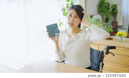 お金について考える車椅子に乗る女性 105997880