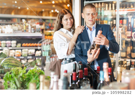 Couple choosing bottle of wine in supermarket Couple choosing bottle of wine in supermarket 105998282
