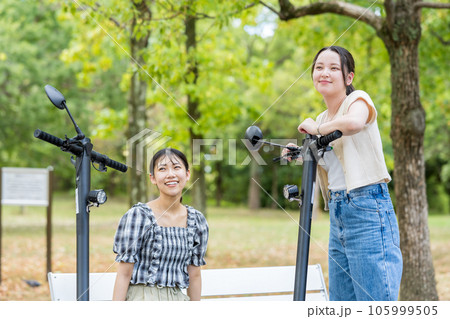 電動キックボードで会い、楽しく会話する若い女性｜電動キックボードイメージ 105999505