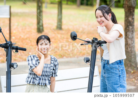 電動キックボードで会い、楽しく会話する若い女性|電動キックボードイメージ 電動キックボードで会い、楽しく会話する若い女性|電動キックボードイメージ 105999507