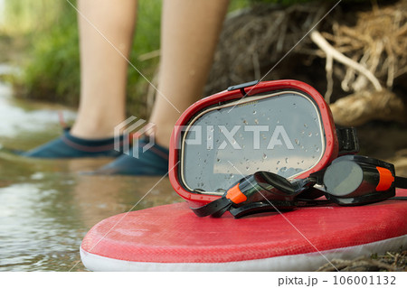 Diving mask and swimming goggles on red surfboard 106001132