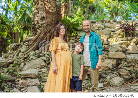 A loving family enjoying a leisurely walk in the park - a radiant pregnant woman after 40, embraced by her husband, and accompanied by their adult teenage son, savoring precious moments together A loving family enjoying a leisurely walk in the park - a radiant pregnant woman after 40, embraced by her husband, and accompanied by their adult teenage son, savoring precious moments together 106001340
