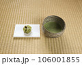抹茶の入った抹茶茶碗と懐紙の上に和菓子 106001855