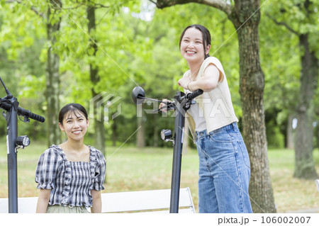 電動キックボードで会い、楽しく会話する若い女性｜電動キックボードイメージ 106002007