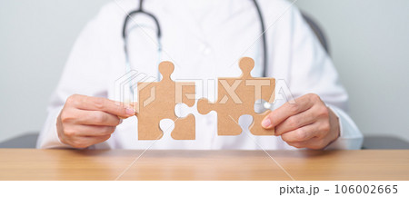Doctor hand connecting couple puzzle piece, wooden jigsaw in hospital. Teamwork, Idea, Solution, challenge, success, Health, Medical and strategy concepts 106002665