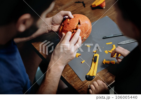 Jack's Halloween pumpkin. Man and child carving face with paper knife. Jack's Halloween pumpkin. Man and child carving face with paper knife. 106005440