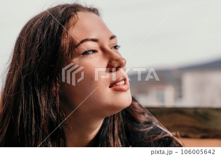 Happy young smiling woman with freckles outdoors portrait. Soft sunny colors. Outdoor close-up portrait of a young brunette woman and looking to the camera, posing against autumn nature background 106005642
